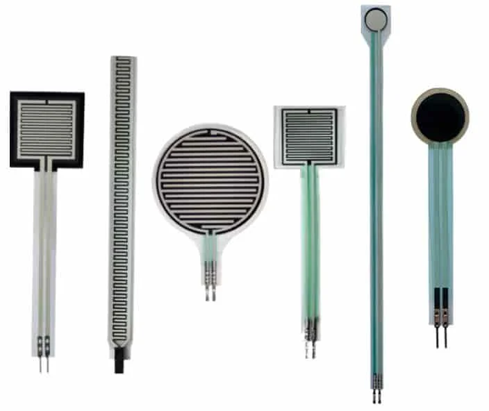 Various force sensors displayed side by side, including resistive force sensors, strain gauges, and piezoelectric sensors, used for measuring pressure and force in different applications.